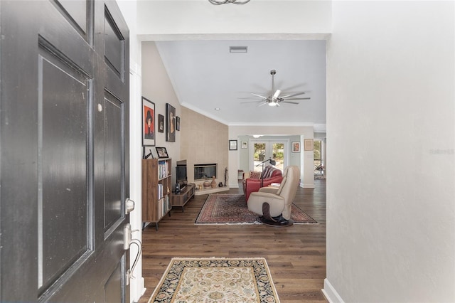 living room with ornamental molding, dark wood-type flooring, and ceiling fan