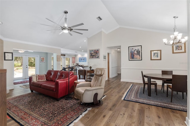 living room featuring ceiling fan with notable chandelier, wood-type flooring, ornamental molding, and french doors