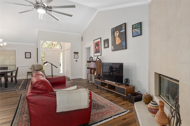 living room with hardwood / wood-style floors, crown molding, vaulted ceiling, and a tile fireplace