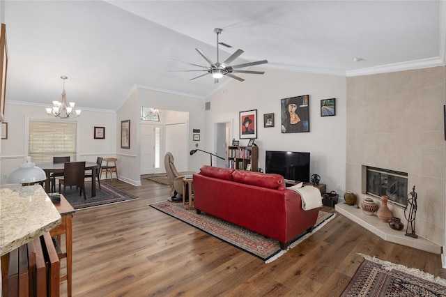 living room with hardwood / wood-style flooring, a fireplace, ornamental molding, and vaulted ceiling