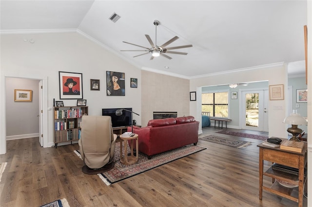 living room with a tiled fireplace, vaulted ceiling, crown molding, and dark hardwood / wood-style flooring