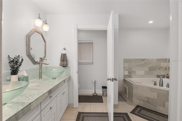 bathroom featuring tile patterned flooring, vanity, and tiled tub