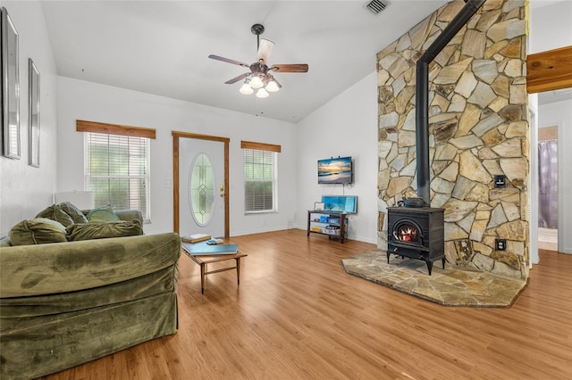 living room featuring vaulted ceiling, a wood stove, ceiling fan, and light hardwood / wood-style flooring