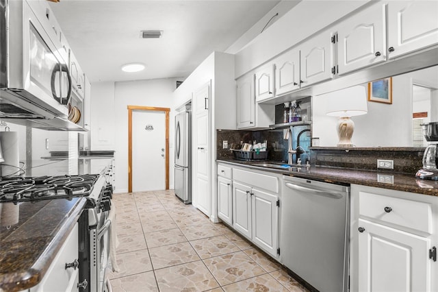 kitchen with appliances with stainless steel finishes, tasteful backsplash, sink, white cabinets, and light tile patterned floors