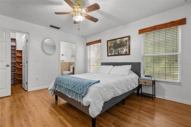 bedroom with a closet, a walk in closet, ensuite bath, and light hardwood / wood-style flooring