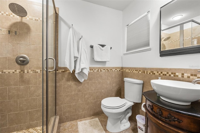 bathroom featuring vanity, a shower with door, toilet, and tile walls