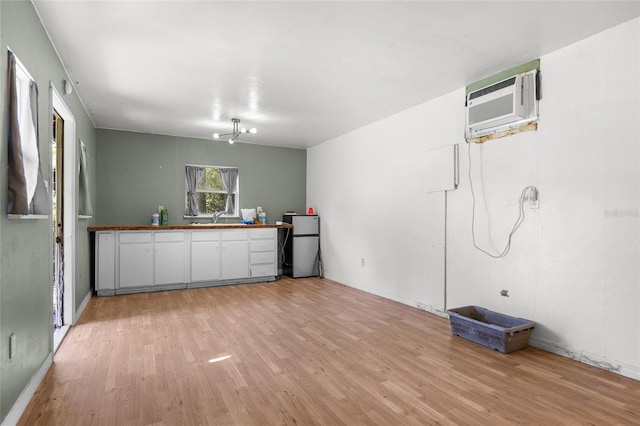 interior space with stainless steel refrigerator, sink, a wall mounted AC, and light hardwood / wood-style floors