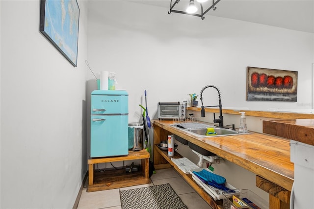 interior space with refrigerator, sink, and light tile patterned floors