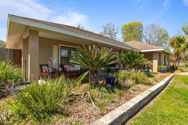 view of side of home featuring stucco siding and a shingled roof