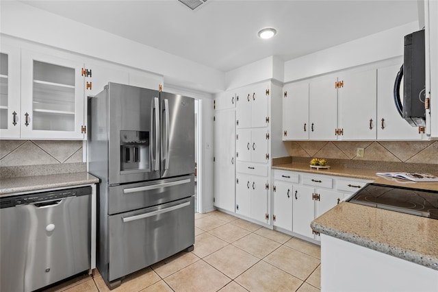 kitchen featuring white cabinetry, appliances with stainless steel finishes, light tile patterned floors, and decorative backsplash