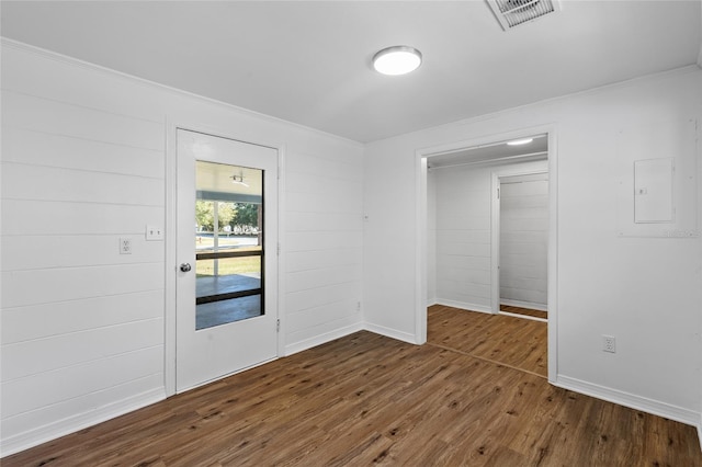 empty room featuring ornamental molding, electric panel, and dark hardwood / wood-style flooring