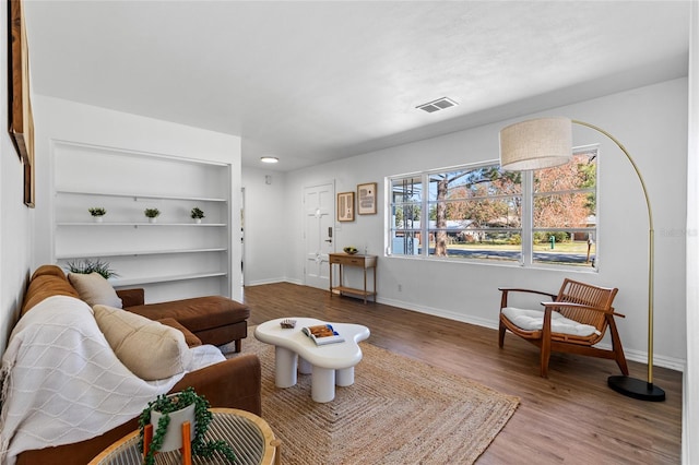 living room with wood-type flooring and built in features