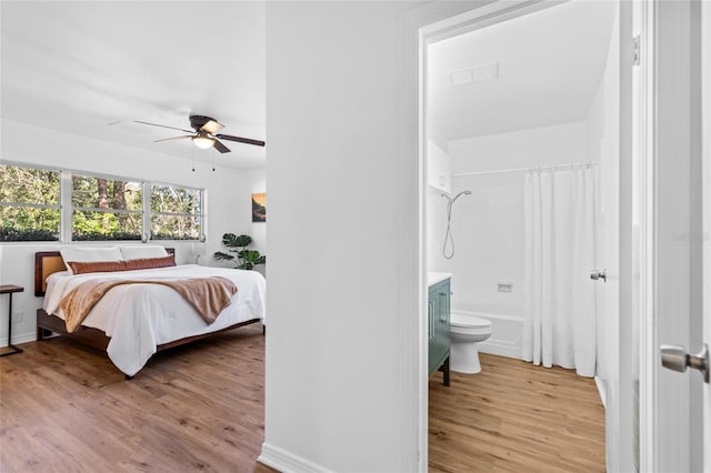 bedroom with ensuite bathroom, ceiling fan, and light hardwood / wood-style flooring