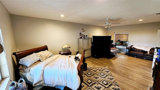 bedroom with hardwood / wood-style floors, a textured ceiling, and ceiling fan