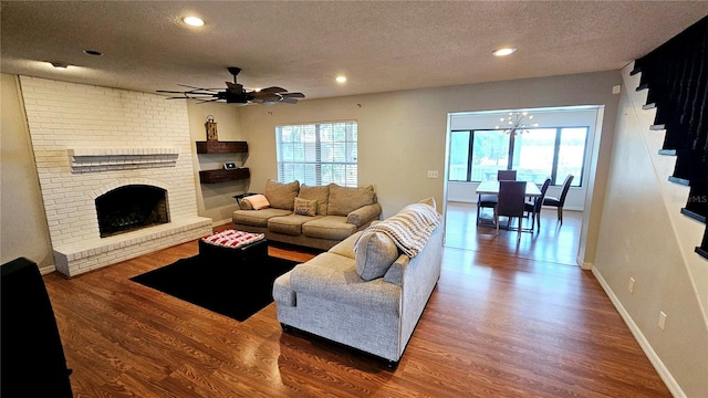 living room featuring hardwood / wood-style flooring, plenty of natural light, a brick fireplace, and a textured ceiling