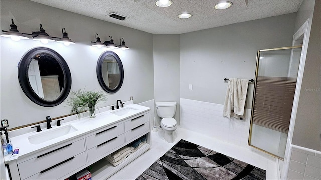 bathroom featuring vanity, toilet, an enclosed shower, and a textured ceiling