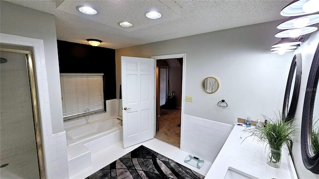 bathroom with vanity, a textured ceiling, and separate shower and tub