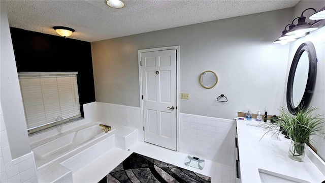 bathroom with vanity, a bathing tub, a textured ceiling, and tile walls