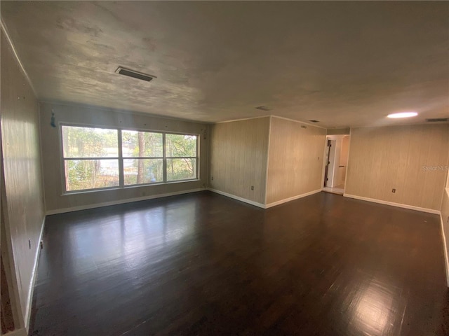 unfurnished room featuring dark hardwood / wood-style floors and wood walls