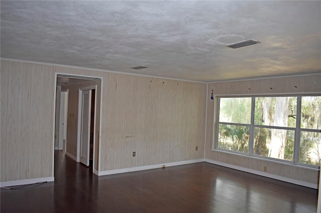 spare room featuring dark wood-type flooring, crown molding, and a textured ceiling