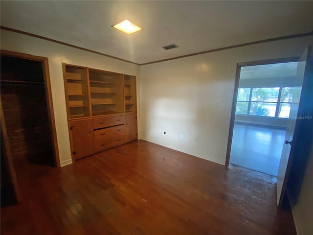 unfurnished bedroom featuring crown molding and dark hardwood / wood-style floors