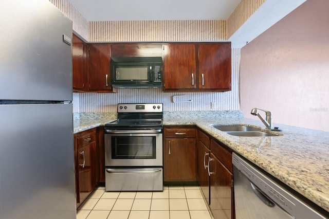 kitchen with light tile patterned flooring, appliances with stainless steel finishes, light stone countertops, and sink