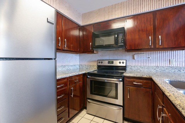 kitchen with light stone counters, stainless steel appliances, and light tile patterned floors