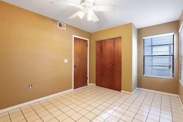 unfurnished bedroom with light tile patterned floors, ceiling fan, and a closet