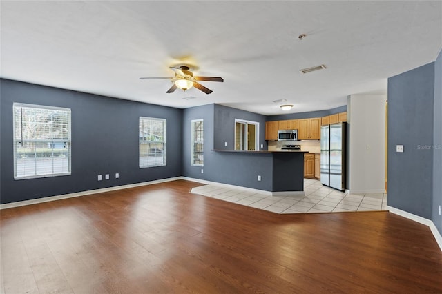 unfurnished living room featuring ceiling fan, light hardwood / wood-style floors, and a wealth of natural light