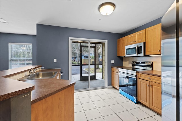 kitchen with appliances with stainless steel finishes, sink, and light tile patterned floors