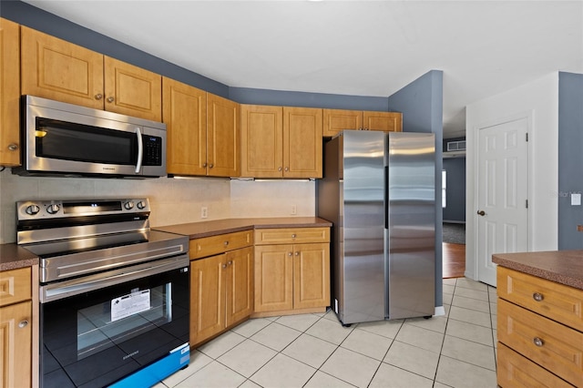 kitchen with tasteful backsplash, light tile patterned floors, and stainless steel appliances