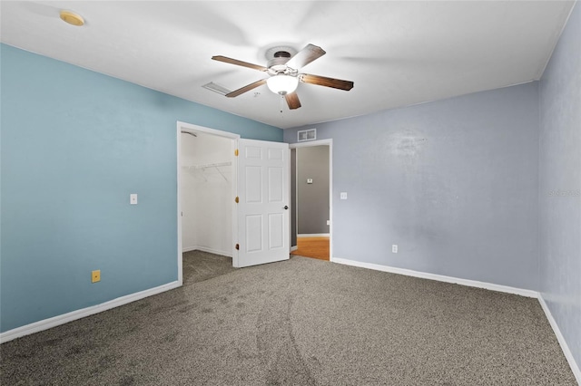 unfurnished bedroom with a spacious closet, a closet, ceiling fan, and carpet flooring