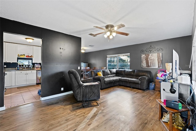 living room with ceiling fan, light hardwood / wood-style floors, and a textured ceiling