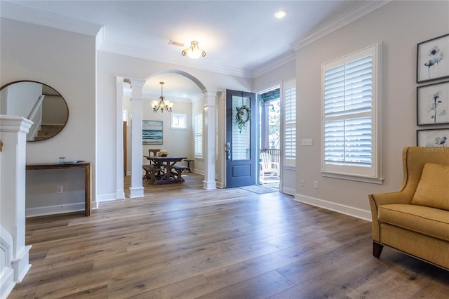 foyer featuring decorative columns, baseboards, arched walkways, ornamental molding, and wood finished floors