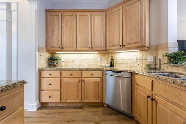 kitchen featuring light stone counters, light wood finished floors, stainless steel dishwasher, light brown cabinets, and a sink