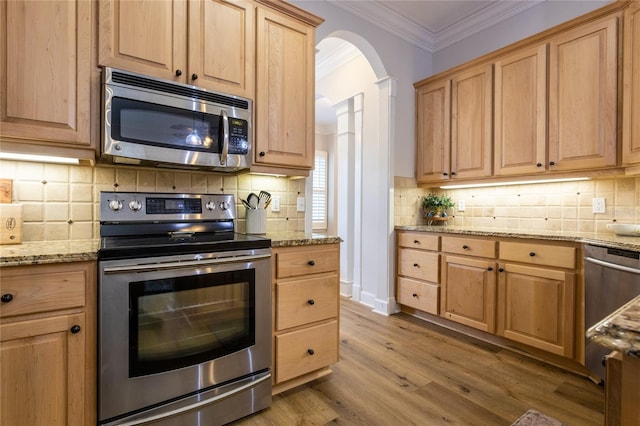 kitchen featuring stainless steel appliances, wood finished floors, ornamental molding, light brown cabinetry, and tasteful backsplash