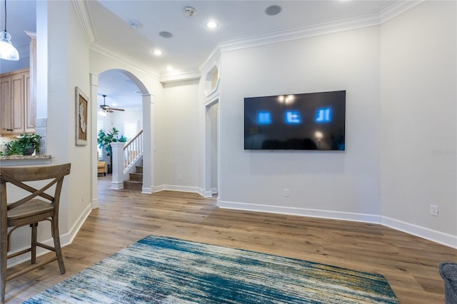 living area with light wood-type flooring, arched walkways, ornamental molding, and stairway