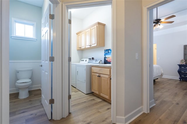 laundry area with ceiling fan, washing machine and dryer, a wainscoted wall, light wood-style floors, and cabinet space