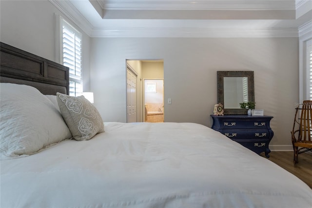 bedroom featuring a tray ceiling, ensuite bathroom, ornamental molding, wood finished floors, and baseboards