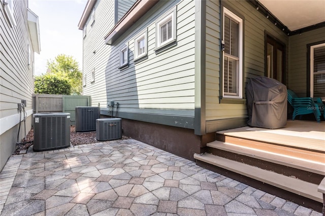 view of side of property with a patio area, cooling unit, and fence