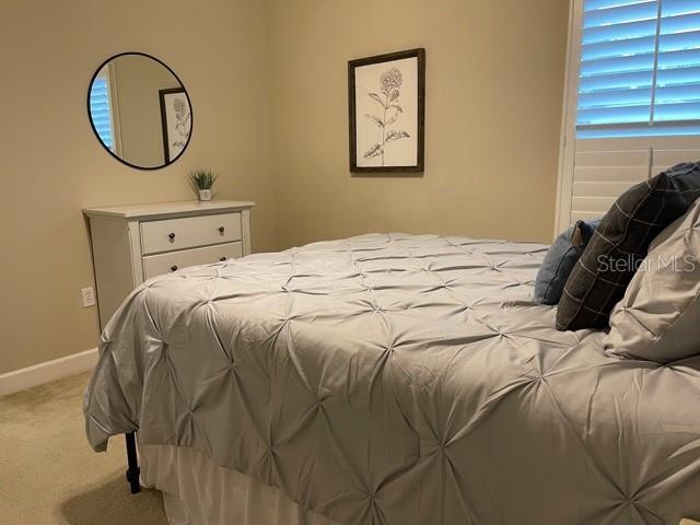 bedroom with light carpet and baseboards