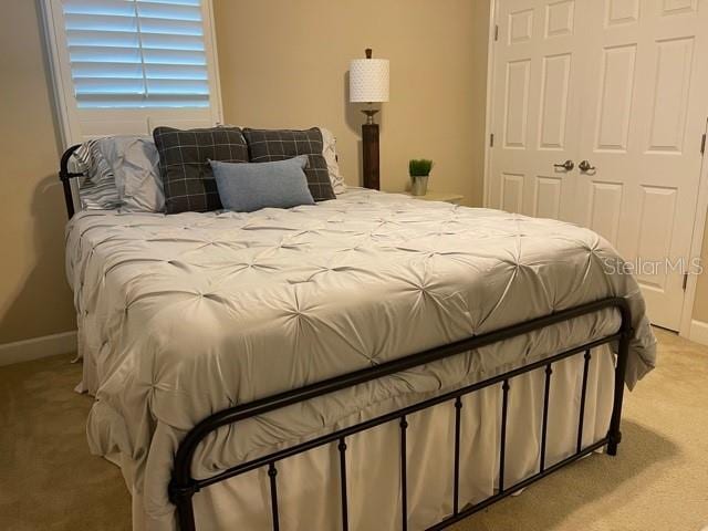 bedroom with light carpet, a closet, and baseboards