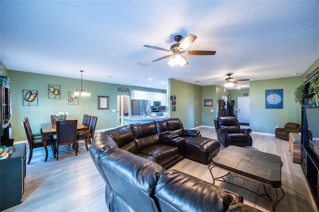 living room featuring ceiling fan with notable chandelier and light wood-type flooring