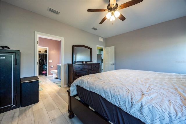 bedroom with connected bathroom, a spacious closet, light hardwood / wood-style floors, and ceiling fan