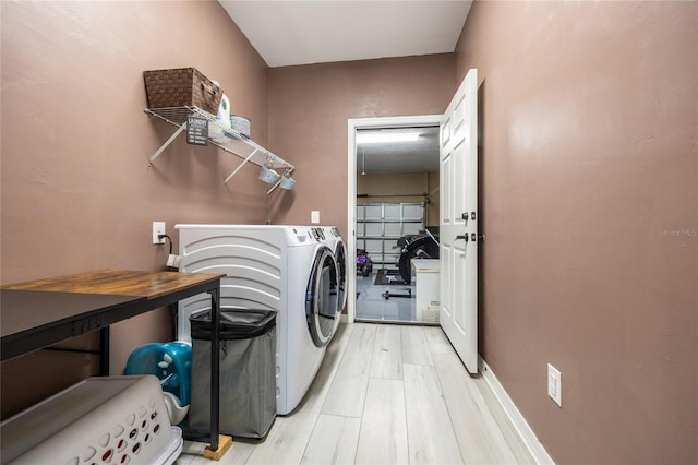 clothes washing area featuring light hardwood / wood-style flooring and washer and dryer