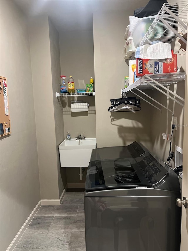 laundry area with laundry area, baseboards, a sink, and washing machine and clothes dryer