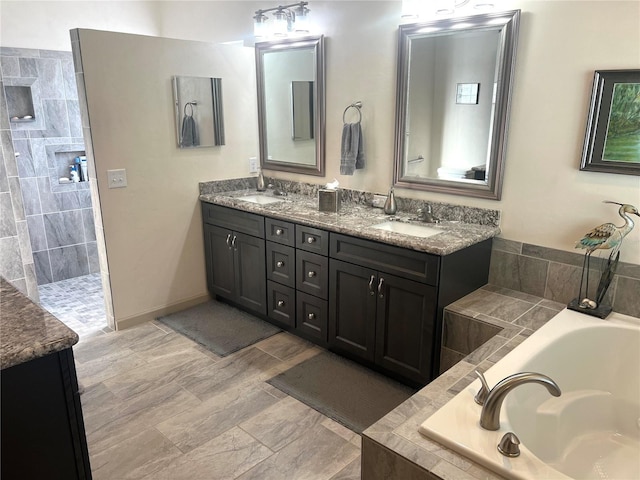 full bath featuring a garden tub, double vanity, a sink, and baseboards