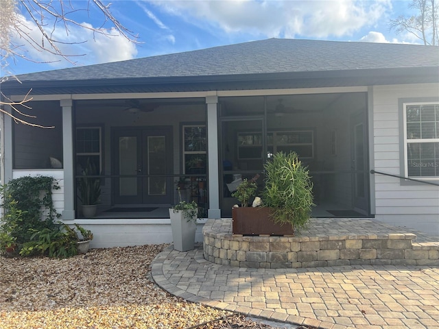 view of exterior entry featuring roof with shingles