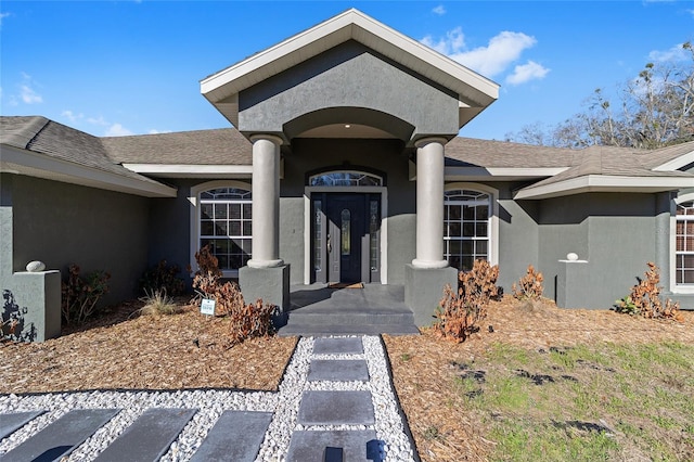 property entrance with a shingled roof and stucco siding