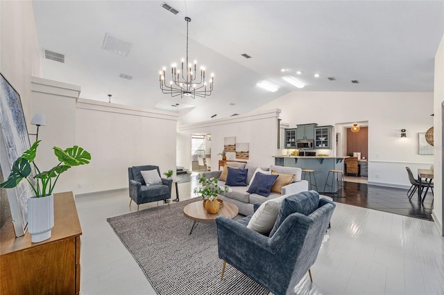 living area featuring visible vents, vaulted ceiling, and a chandelier